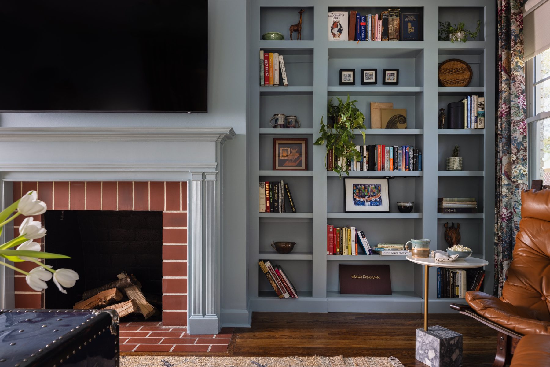 The same wall of powder blue built-ins beside the fireplace with the hidden door closed and completely invisible among the styled shelves